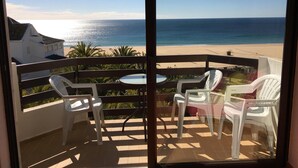 A balcony with a glass door, white plastic chairs, a small round table, and a view of the beach and ocean. - 6th floor apartment, facing the sea with balcony "exceptional 360 ° view" (Portimão)