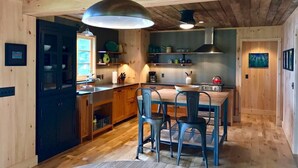 A wooden interior with a dining table, chairs, a kitchen area, and a ceiling fan. - Artisan-crafted Magic on Lake Superior (Lutsen)