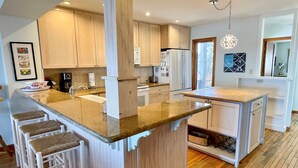 Une cuisine moderne dotée d’un îlot central, de meubles en bois et d’un coin bar avec des tabourets.