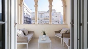 A balcony with three arched windows, wicker furniture, and a potted plant. - Sweethome26 - Hayarkon with Terrace (Tel Aviv)