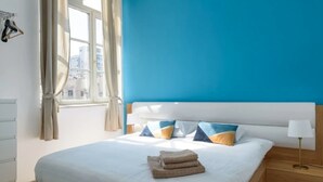 A bedroom with a large bed, a window with curtains, and a view of buildings outside. - Sweethome26 - Hayarkon with Terrace (Tel Aviv)