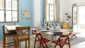 A dining area with a table set for four, red chairs, a white tablecloth, and a blue wall. - Sweethome26 - Hayarkon with Terrace (Tel Aviv)