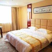 A hotel room with a large bed, a bedside table, a window with curtains, and a framed picture on the wall.