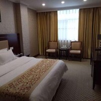 A hotel room with a large bed, two chairs, a small table, and a nightstand.