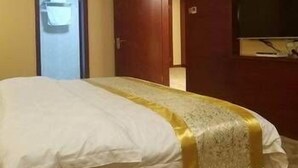 A hotel room with a bed, a television mounted on the wall, and a door leading to another room. - Greentree Alliance Hotel (Suzhou)