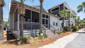 A row of two-story houses with a porch, palm trees, and a clear sky. - Seacrest Beach Home + Dog Friendly, Tram & Bikes (Seacrest Beach)