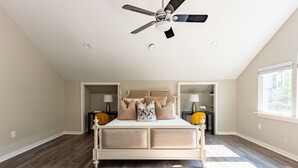 Een slaapkamer met een groot bed, een plafondventilator en een raam.