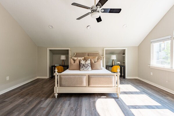 A bedroom with a large bed, a ceiling fan, and a window.