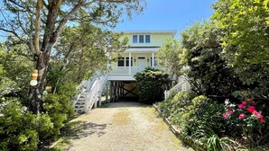 A two-story house with a covered porch and a gravel pathway leading to the entrance. - Sea View: Rooftop deck with spectacular views. (Ocracoke)