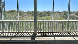A wooden deck with a railing, large windows, and a view of a forested landscape. - Sea View: Rooftop deck with spectacular views. (Ocracoke)