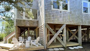 A two-story wooden house with a covered deck, outdoor seating area, and a wooden fence. - Safe Harbor:  Expansive views of the salt marsh, maritime forest. (Ocracoke)