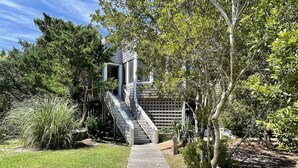 A wooden pathway leading to a house with a staircase and a covered porch. - Safe Harbor:  Expansive views of the salt marsh, maritime forest. (Ocracoke)