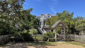 A residential area with a wooden fence, a gravel driveway, and a house with a grey roof and white trim. - Safe Harbor:  Expansive views of the salt marsh, maritime forest. (Ocracoke)