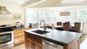A modern kitchen with a large island, built-in appliances, and large windows. - Safe Harbor:  Expansive views of the salt marsh, maritime forest. (Ocracoke)