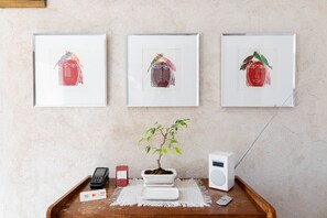 Three framed artworks on a wall, a bonsai tree on a table, and a white speaker. - Clos des Moulins (Poitiers)