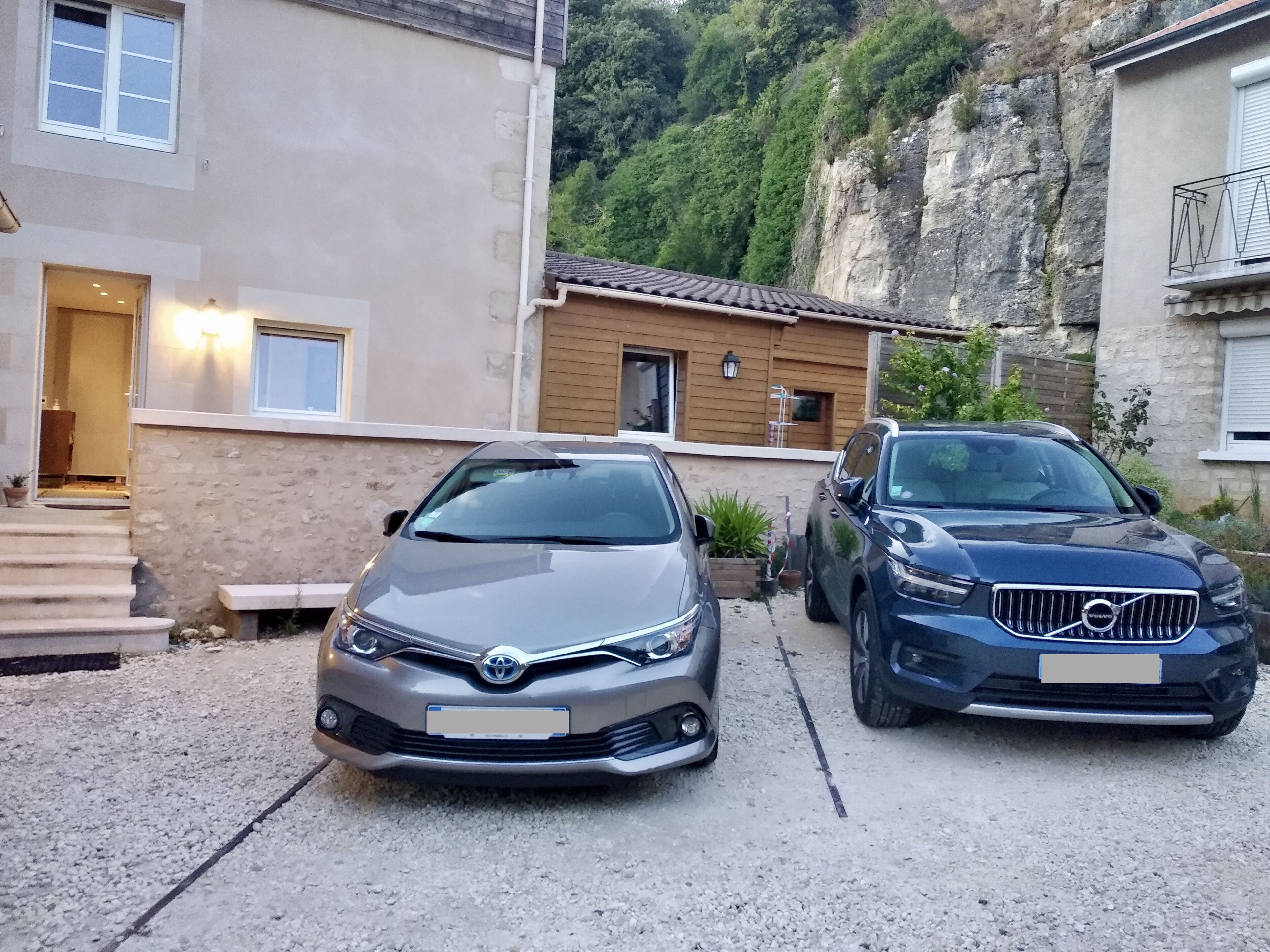 Two cars parked in a driveway with a house in the background.