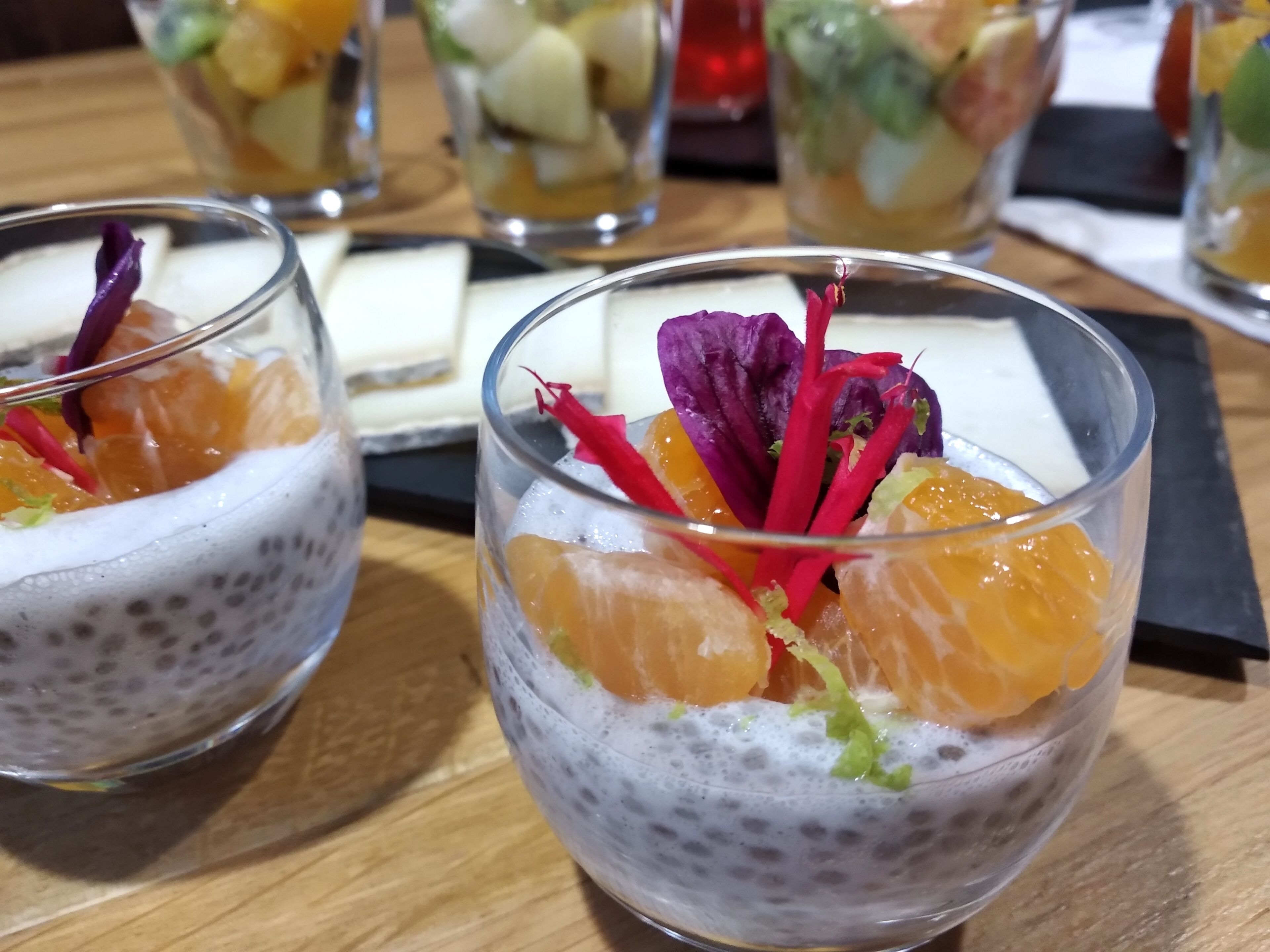 Un postre con fruta y una flor decorativa en un bol de vidrio.