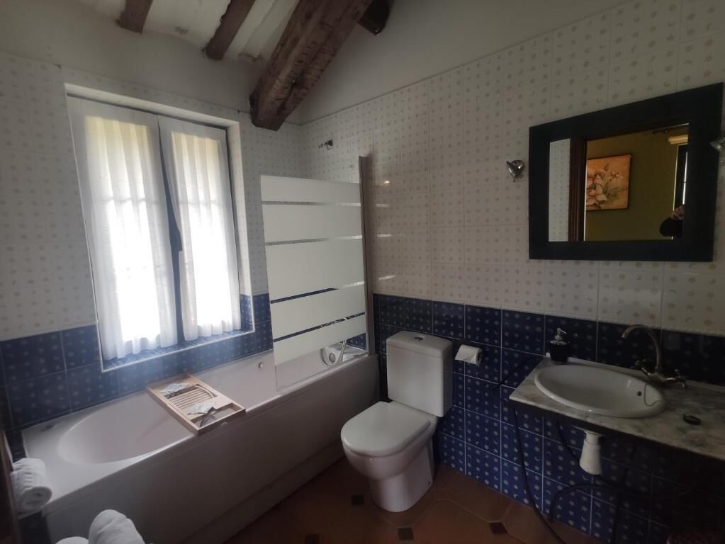 Un baño con bañera, inodoro, lavamanos y ventana.