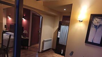 Une chambre d’hôtel avec un lit, un bureau, une chaise, un radiateur et un tableau encadré au mur.