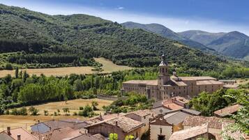 A historic building with a prominent tower, surrounded by terraced fields and lush green hills.