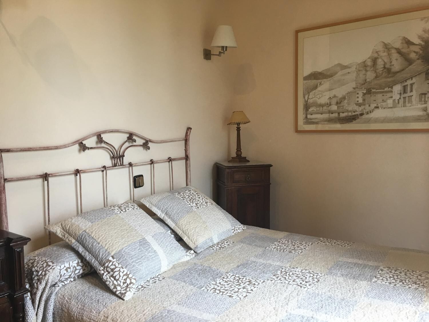 A bedroom with a bed, a nightstand, a lamp, and a framed picture on the wall.
