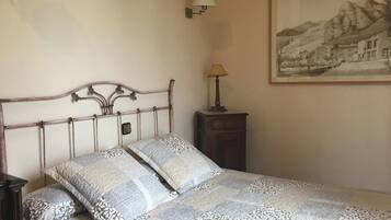 A bedroom with a bed, a nightstand, a lamp, and a framed picture on the wall.