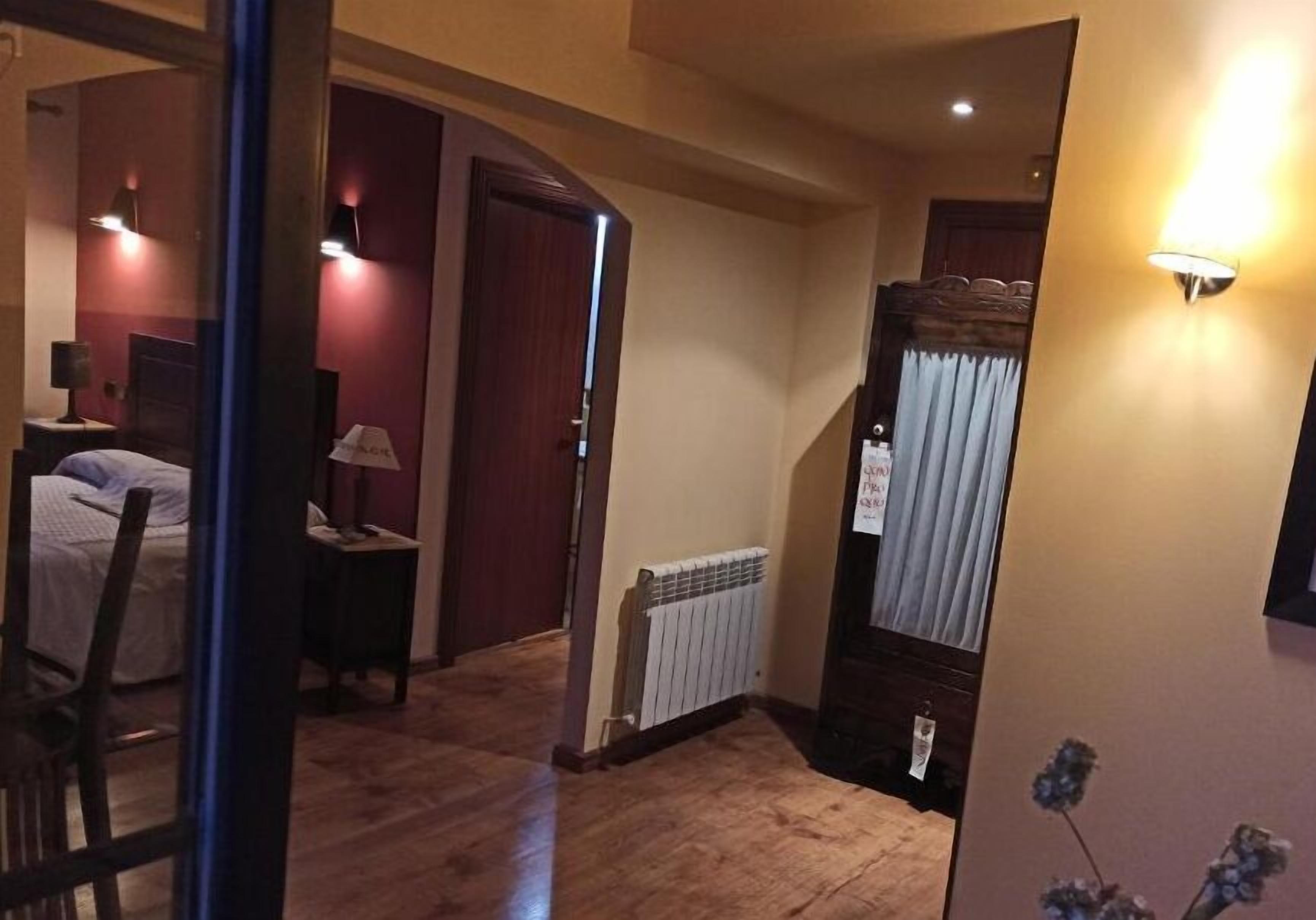Een hotelkamer met een bed, een nachtkastje, een lamp, een radiator en een trap naar een andere kamer.