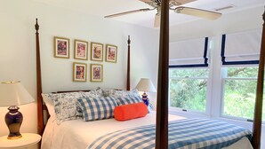 A four-poster bed with a checkered bedspread, a red pillow, and multiple framed pictures on the wall. - Fresh Fruit:  Pet Friendly, pleasant single story on private lane. (Ocracoke)
