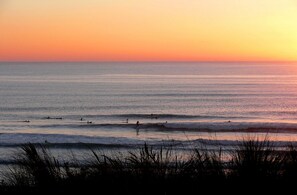 A beach scene with waves and surfers at sunset. - Maison Aurora by Agence Bru - 2078 (Lacanau)