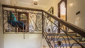 Un escalier orné de rampes en métal noir ouvragé et de carreaux aux motifs bleus et blancs.