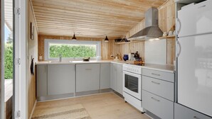 Moderni keittiö, jossa on puinen katto, valkoiset kaapit ja sisäänrakennettu uuni.