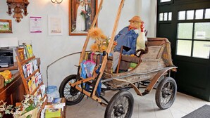 A rustic interior with a wooden cart, a clock, and a framed photograph on the wall. - 07 Holiday apartment - holiday farm on Rügen (Putbus)