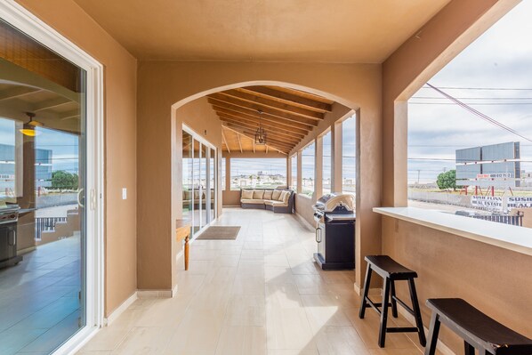 A covered outdoor area with a barbecue grill, seating, and a view of the city.