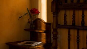 Quarto com cabeceira de madeira, mesa de cabeceira com um vaso de flores e cama com roupa de cama listrada.