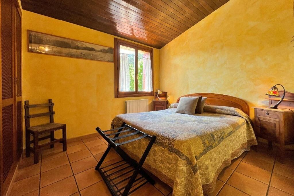 Une chambre à coucher avec un lit, une chaise, une fenêtre et une table de chevet.