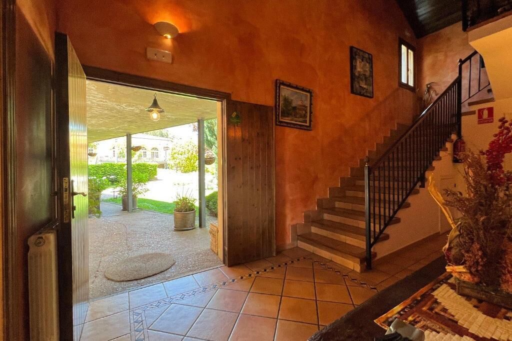 Una escalera conduce a un segundo piso, una puerta se abre a un espacio exterior cubierto y una lámpara está fijada a la pared.