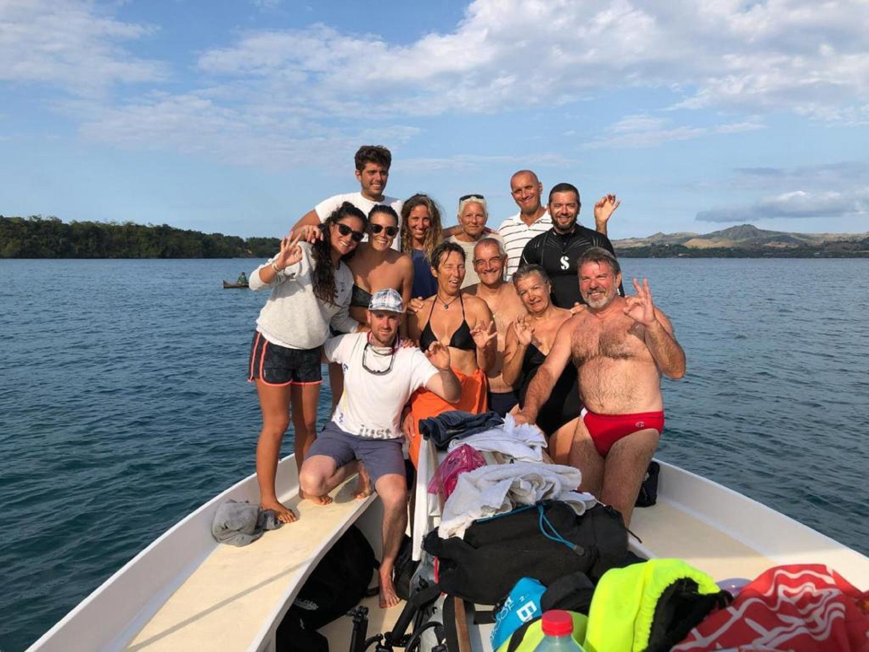 A group of people on a boat with a lake and hills in the background.