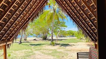 Una estructura al aire libre con techo de paja, una mesa redonda y dos sofás estampados.