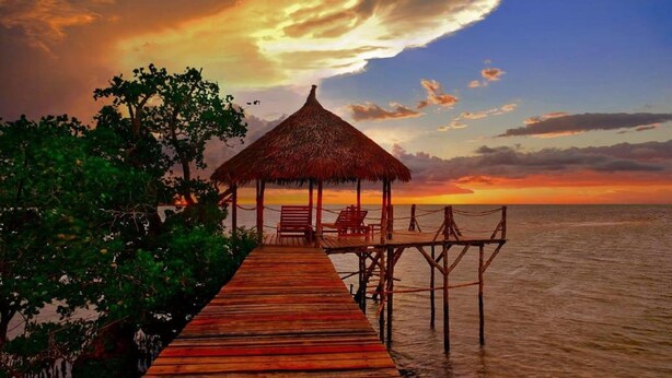 A wooden pier leading to a thatched-roof structure with chairs, overlooking the sea. - Emeraude Lodge (Nosy Be)