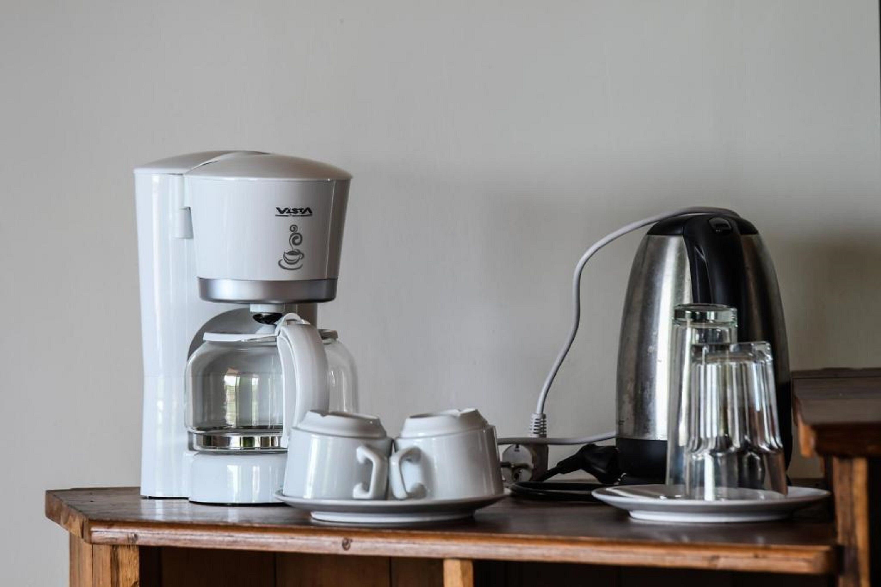 A coffee maker and a kettle on a wooden table.