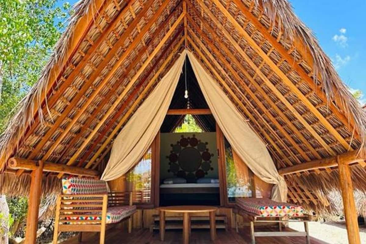 A thatched-roof hut with a wooden deck and seating area.