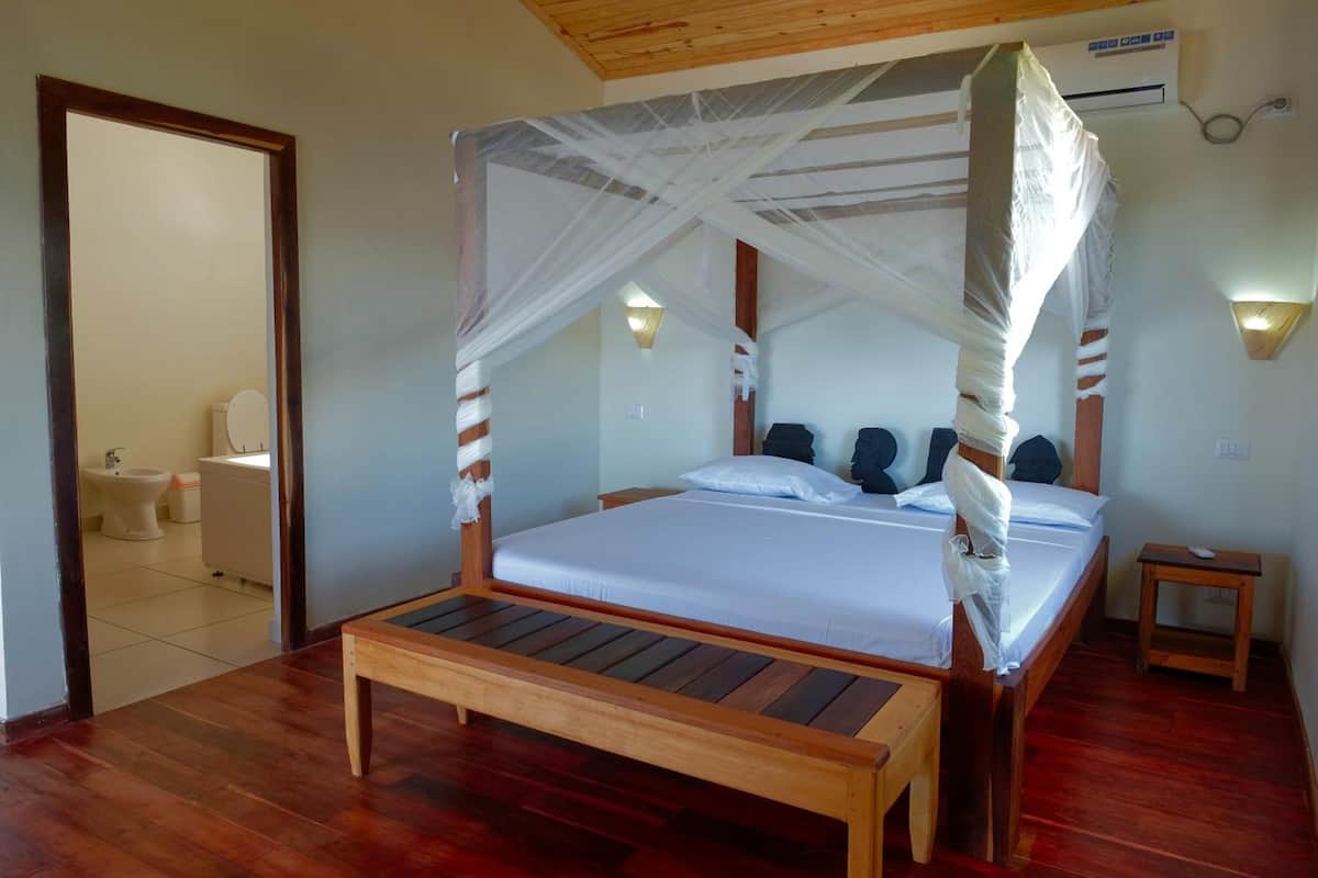 A wooden four-poster bed with white bedding, a small bedside table, and a nightstand.