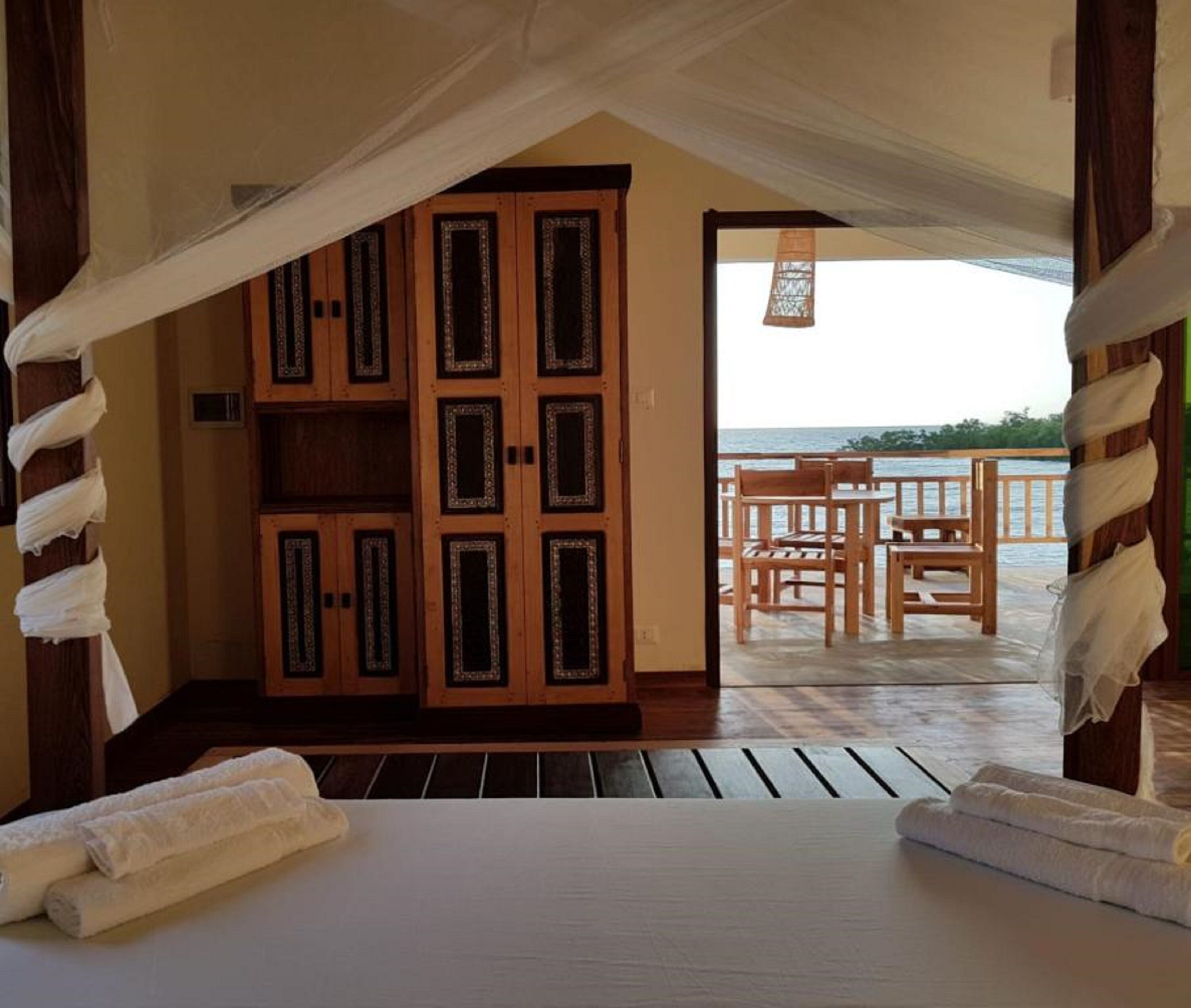 Ein Zimmer mit einem Bett, einem Holzschrank und einem Balkon mit Tisch und Stühlen.