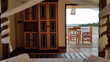 Ein Zimmer mit einem Bett, einem Holzschrank und einem Balkon mit Tisch und Stühlen.