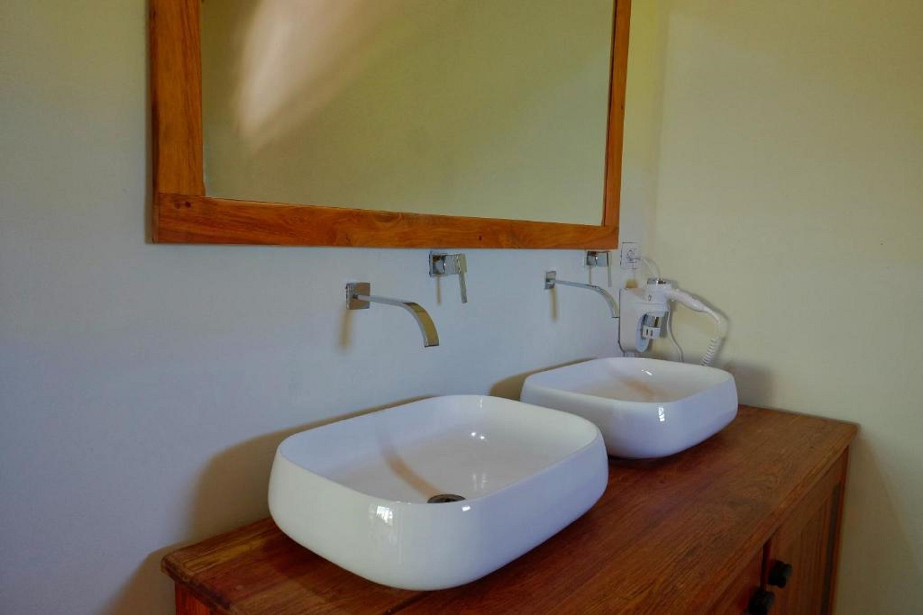Two white ceramic sinks mounted on a wooden vanity with a mirror above them.