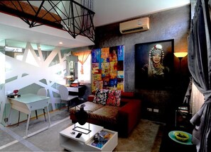 A modern living room with a red sofa, a white coffee table, and a colorful abstract painting on the wall. - Phuket Paradiso Hotel (Chalong)