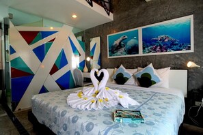 A hotel room with a bed, a wall with geometric patterns, and two framed pictures of sea turtles. - Phuket Paradiso Hotel (Chalong)