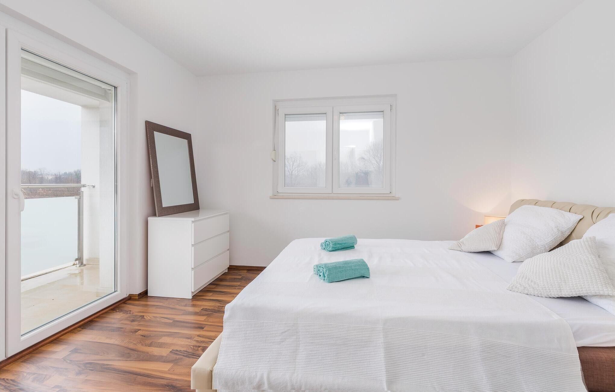 Un dormitorio con cama, cómoda, espejo y ventana.