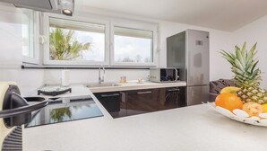 Una cocina moderna con un ventanal grande, electrodomésticos de acero inoxidable y un frutero sobre la encimera.