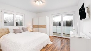Un dormitorio con una cama grande, un armario, un televisor y un balcón con vistas.